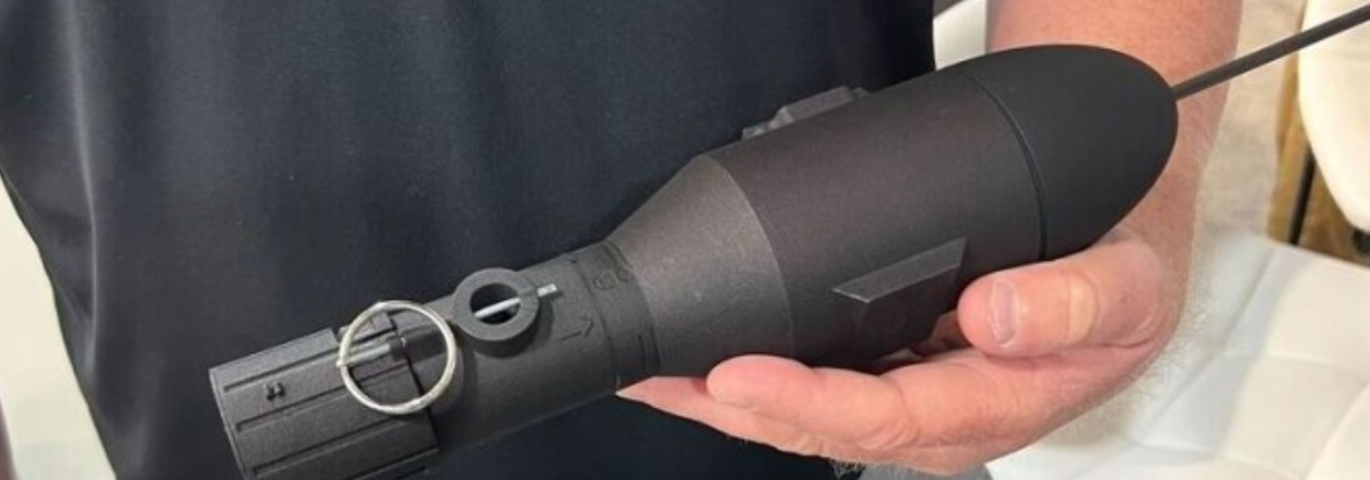 Close up of a persons hand holding a black cylindrical handheld device with a metal circular ring near the front